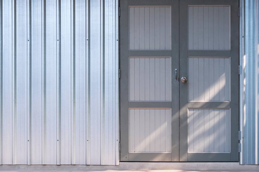 Steel Doors & Frames Background of the old wooden door on corrugated steel wall of storehouse with sunlight on surface
